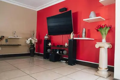 a living room with a red wall with a flat screen tv at Ray of sunshine in Centurion