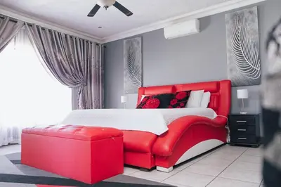a red bed with a red ottoman in a bedroom at Ray of sunshine in Centurion