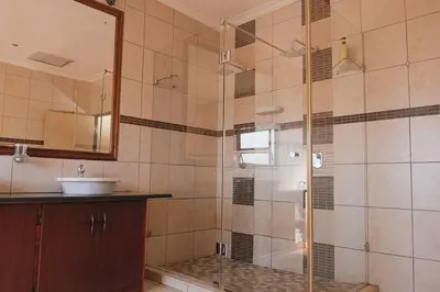 a bathroom with a glass shower with a sink at Ray of sunshine in Centurion