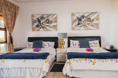 a bedroom with two beds and two pictures on the wall at Ray of sunshine in Centurion