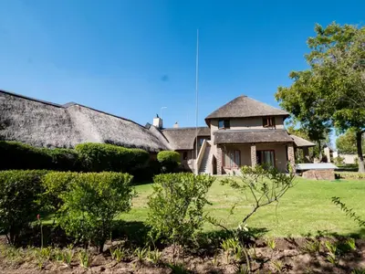 an old house with a thatched roof in a yard at Celtis Manor Guesthouse in Midrand