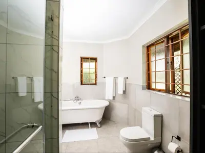 a bathroom with a tub and a toilet and a sink at Celtis Manor Guesthouse in Midrand