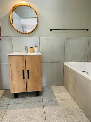 a bathroom with a sink and a mirror and a tub at Celtis Manor Guesthouse in Midrand