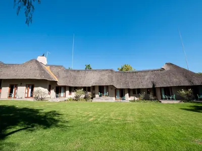 a large building with a thatched roof with a yard at Celtis Manor Guesthouse in Midrand