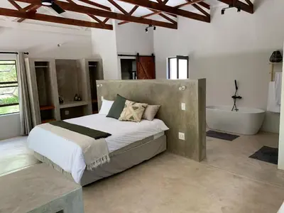 a bedroom with a large bed and a bath tub at Pango Kruger Home For 2 in Marloth Park