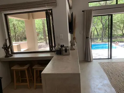 a kitchen with a counter and a view of a pool at Pango Kruger Home For 2 in Marloth Park
