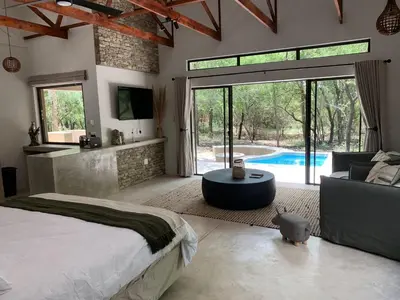 a bedroom with a large bed and a swimming pool at Pango Kruger Home For 2 in Marloth Park