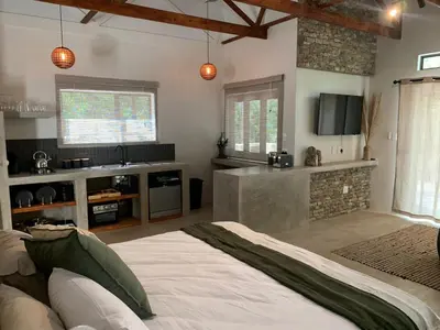 a bedroom with a large bed and a kitchen at Pango Kruger Home For 2 in Marloth Park