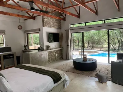 a bedroom with a large bed and a swimming pool at Pango Kruger Home For 2 in Marloth Park