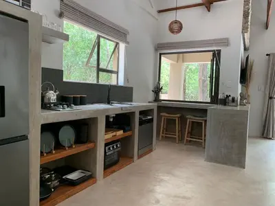 a kitchen with a counter with a sink and some windows at Pango Kruger Home For 2 in Marloth Park