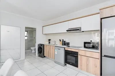 a kitchen with white walls and wooden cabinets at Luxury apartment in Kyalami in Midrand