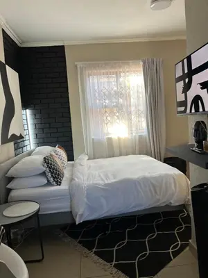 a bedroom with a white bed and a window at Pride studio @ The Monarch in Polokwane