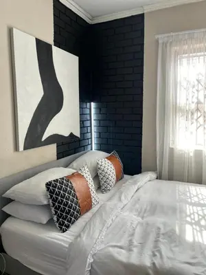 a bedroom with a bed with pillows and a painting at Pride studio @ The Monarch in Polokwane