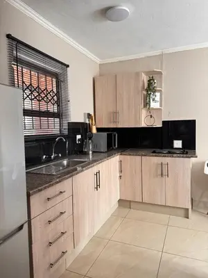 a kitchen with wooden cabinets and a sink at Pride studio @ The Monarch in Polokwane