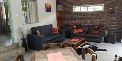 a living room with two couches and a brick wall at Die Boshuisie in Rayton