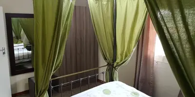 a bed with green curtains in a room at Die Boshuisie in Rayton