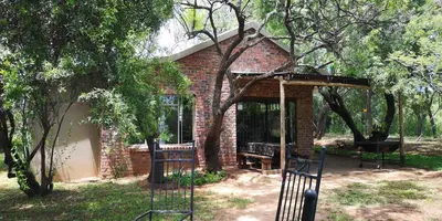 a brick shelter with a bench in a garden at Die Boshuisie in Rayton