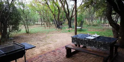a picnic table and a grill in a park at Die Boshuisie in Rayton