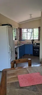 a kitchen with a wooden table and a refrigerator at Die Boshuisie in Rayton