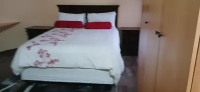 a bedroom with a bed with two red pillows at Bright Light self catering in Pretoria