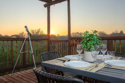 a table with plates and wine glasses on a deck at The Duchess Luxury Safari Villa, Close to KNP, Giraffe-Feeding-Tower, Bush-Bath, Boma in Marloth Park