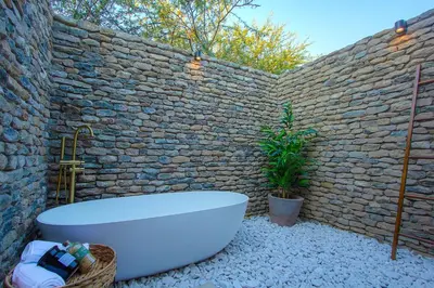 a bathroom with a bath tub and a brick wall at The Duchess Luxury Safari Villa, Close to KNP, Giraffe-Feeding-Tower, Bush-Bath, Boma in Marloth Park