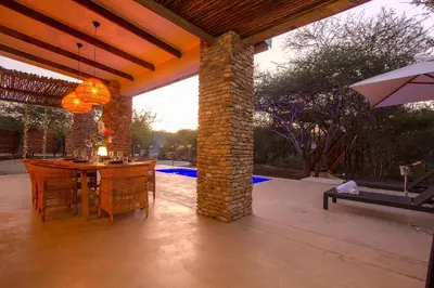 a patio with a table and chairs and an umbrella at The Duchess Luxury Safari Villa, Close to KNP, Giraffe-Feeding-Tower, Bush-Bath, Boma in Marloth Park