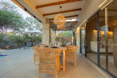 an outdoor kitchen with a wooden table and chairs at The Duchess Luxury Safari Villa, Close to KNP, Giraffe-Feeding-Tower, Bush-Bath, Boma in Marloth Park