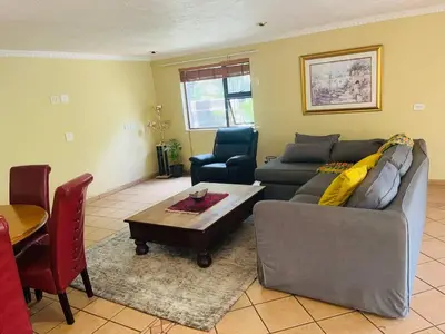 a living room with a couch and a table at Goldpot Garsfontein 6 minutes away from SunBet Arena at Time Square Casino in Pretoria