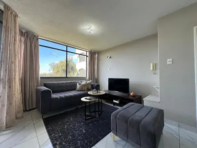 a living room with a couch and a tv at Lux Living at Menlyn Place in Pretoria