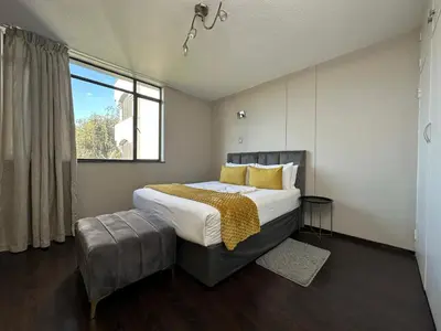 a bedroom with a large bed and a window at Lux Living at Menlyn Place in Pretoria