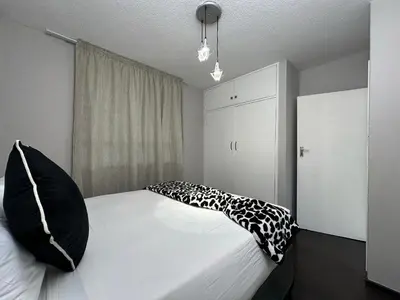 a bedroom with a bed with black and white pillows at Lux Living at Menlyn Place in Pretoria