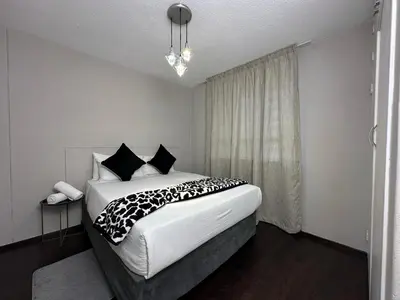 a bedroom with a large bed with black and white pillows at Lux Living at Menlyn Place in Pretoria