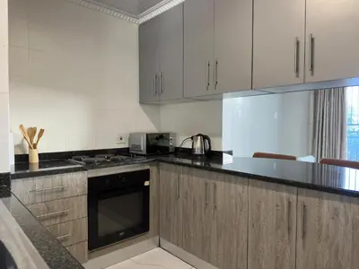 a kitchen with white cabinets and a stove top oven at Lux Living at Menlyn Place in Pretoria