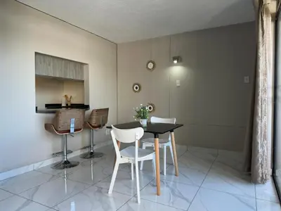 a dining room with a table and white chairs at Lux Living at Menlyn Place in Pretoria