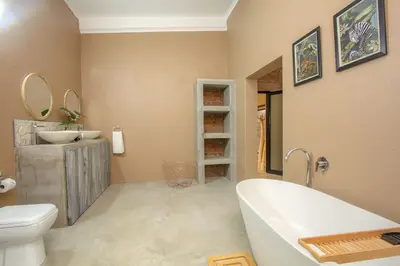 a bathroom with a tub and a toilet and a sink at Leopard Crest in Marloth Park