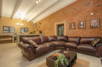 a leather couch in a living room with a brick wall at Leopard Crest in Marloth Park