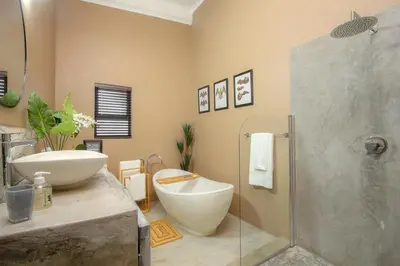 a bathroom with a tub and a sink and a shower at Leopard Crest in Marloth Park