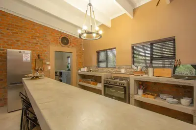 a large kitchen with a counter top and a brick wall at Leopard Crest in Marloth Park