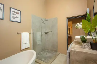 a bathroom with a shower and a tub and a sink at Leopard Crest in Marloth Park