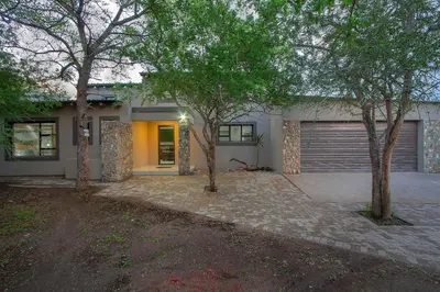 a house with a garage and two trees in front of it at Cheetah Plateau in Marloth Park