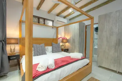 a bedroom with a canopy bed with a red blanket at Cheetah Plateau in Marloth Park