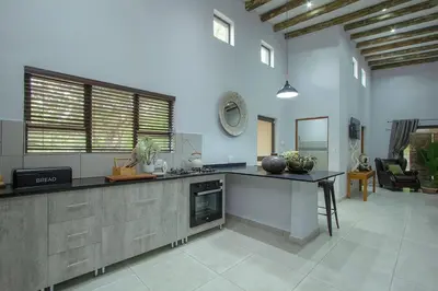 a large kitchen with a counter and a living room at Cheetah Plateau in Marloth Park