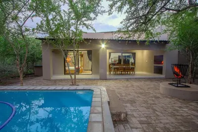 a house with a swimming pool in front of a house at Cheetah Plateau in Marloth Park