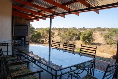 a screened porch with a glass table and chairs at Casa de la Presa 6 in Polokwane