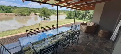 a patio with a table and chairs and a view of a river at Casa de la Presa 6 in Polokwane