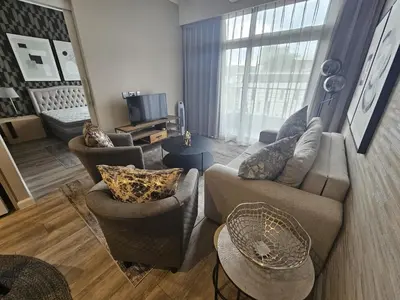 a living room with a couch and chairs and a television at Capital Trilogy Apartments in Pretoria