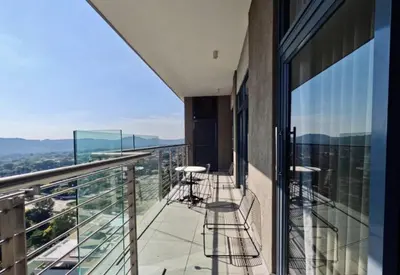 a balcony with chairs and tables on a building at Capital Trilogy Apartments in Pretoria