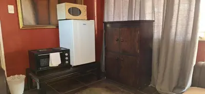 a room with a microwave and a refrigerator next to a cabinet at Henning nest guest house in Centurion