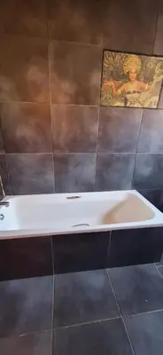 a bath tub in a bathroom with a picture on the wall at Henning nest guest house in Centurion
